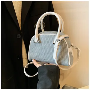 Gros plan d'un petit sac à bandoulière bleu clair avec poignées blanches et zip argenté