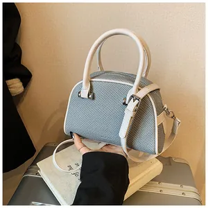 Détail du sac Boston bleu clair tissé avec lanières en cuir blanc et zip argenté