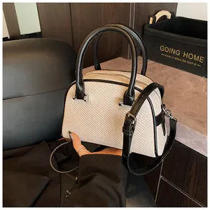 Détail d'un sac à main coquillage minimaliste en cuir crème texturé et anses noires