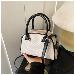 Détail du sac boston beige avec poignées en cuir noir et finitions métalliques argent