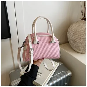 Détail du sac bandoulière tissé rose avec poignées blanches et finitions argentées de voyage