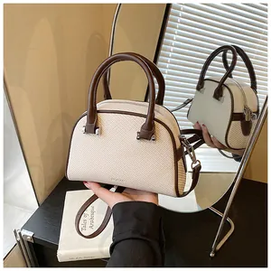 Détail d'un sac à main rétro crème tissé avec anses en cuir marron et logo Romad