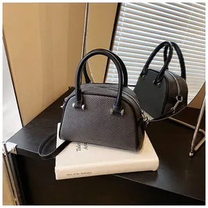 Détail du sac à main tissé gris foncé avec ferrures argentées et poignées rondes
