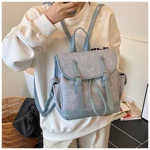 Detail of light blue and gray canvas backpack with floral embroidery and dual buckle straps