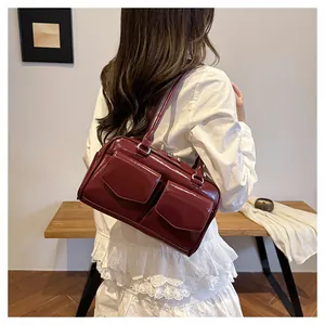 Detail einer dunkelroten glänzenden Umhängetasche mit Fronttaschen am Model