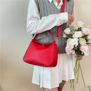 Sac Boston rouge en cuir grainé avec poignée supérieure et bandoulière réglable élégant