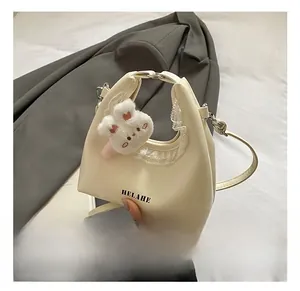 Detailansicht einer cremefarbenen Cloud-Tasche mit Plüschhasen-Anhänger und Spitze