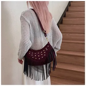 Detail of burgundy suede crescent bag featuring vintage gold rivets and long fringe tassels