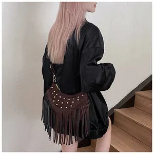 Detail of brown suede crossbody bag featuring gold studs and bohemian fringe tassels