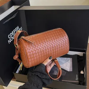 Chic brown woven cylinder shoulder bag with adjustable strap in luxury lifestyle setting