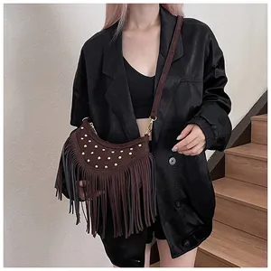 Detailed close-up of brown suede crossbody bag featuring gold studs and retro fringe tassels