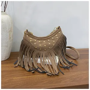 Close-up of brown suede crossbody bag featuring golden rivets and long tassel details