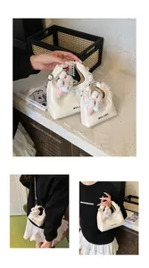 Detail der cremefarbenen Tasche mit Spitzenbesatz und Plüsch-Hasen-Anhänger für Damen