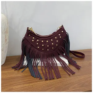 Detail view of burgundy fringed crossbody bag with gold stud rivets and suede texture