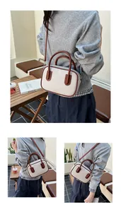 Detail of contrast stitching canvas handbag with brown leather trim and shoulder strap