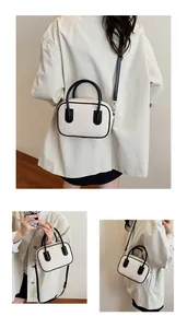 Detail of a color-block square bag showing the textured off-white fabric and black handles