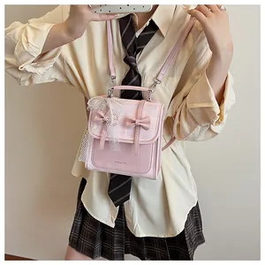 Dettaglio dello zaino in pelle rosa con decorazioni a fiocco e ciondolo di perle e pizzo