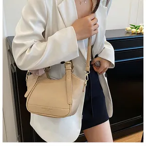 Gros plan sur le cuir beige grainé et la boucle de sangle réglable dorée du sac à main