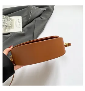 Detail view of brown semi-circular saddle bag with golden metal hardware and side buckles