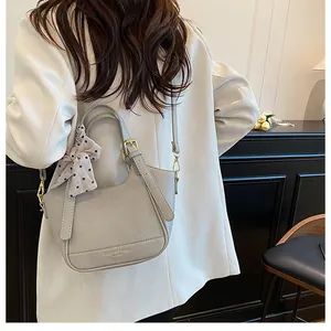 Détail du sac seau en cuir à motif litchi avec foulard décoratif et boucles dorées