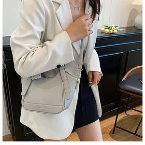 Détail du sac seau en cuir grainé gris clair avec poignée supérieure et boucles dorées