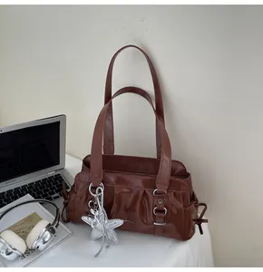 Detail of brown faux leather shoulder bag with silver star charm in a lifestyle office setup
