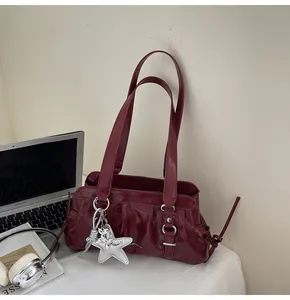 Detail of burgundy glossy underarm bag with silver star charm and drawstring design