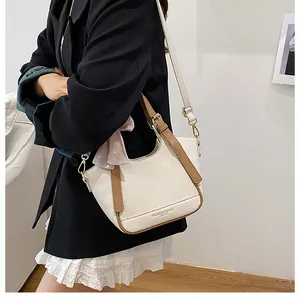 Vue latérale du sac seau beige texture litchi avec poignées marron et détails dorés