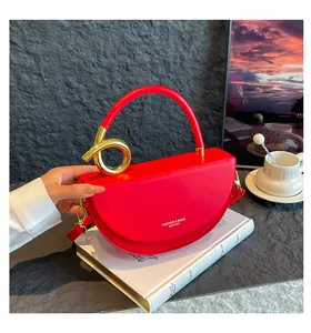 Detail of red leather semi-circle handbag with golden knot handle and fashion engraving