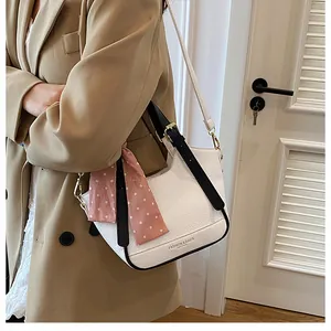 Gros plan d'un sac seau blanc à motif litchi avec bordure noire et foulard à pois roses