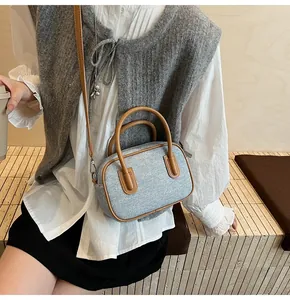Detail of minimalist small square handbag with contrast stitching and leather strap