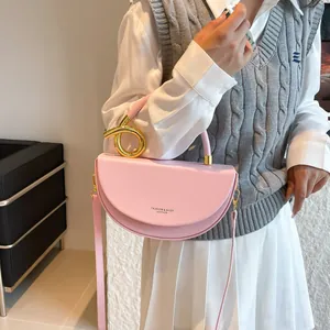 Pink half-moon handbag with gold twisted metal handle and detachable shoulder strap
