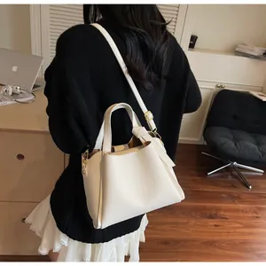 Detail of cream lychee texture leather bucket bag with gold hardware and shoulder strap
