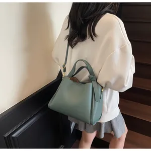 Action shot of the vintage textured grey-green leather bucket bag with knot detail