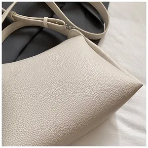 Gros plan du sac seau beige montrant la texture cuir grainé et les finitions argentées