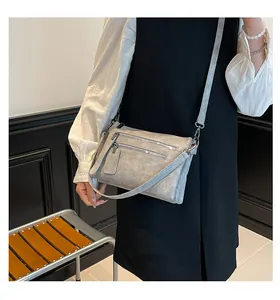 Détail de la bandoulière en cuir lavé gris avec doubles fermetures éclair en métal