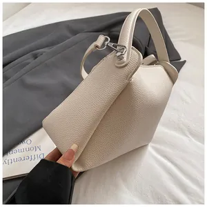 Gros plan d'un sac à main beige en cuir grainé avec fermoir argenté et anse
