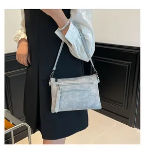 Détail d'un sac bandoulière gris clair texturé avec doubles poches zippées frontales