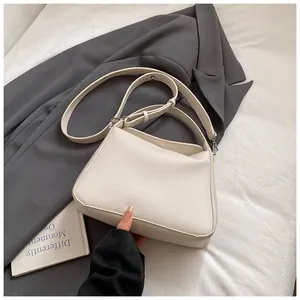 Détail du sac seau en cuir beige grainé avec deux bandoulières sur un blazer