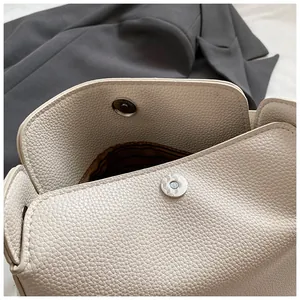 Détail du sac à main crème avec texture litchi, fermoir magnétique et doublure brune