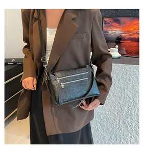 Détail du sac à bandoulière noir plissé avec doubles fermetures éclair et tirettes en cuir