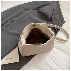 Gros plan de l'intérieur du sac seau crème avec doublure rayée et boucle magnétique