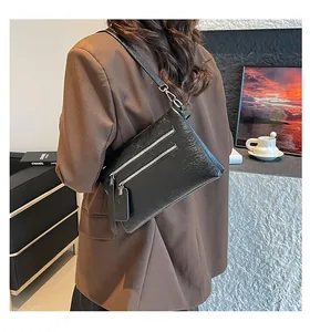 Détail du sac bandoulière en cuir noir texturé avec fermetures éclair argentées
