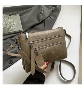 Vue détaillée du sac bandoulière vintage marron avec trois compartiments zippés et similicuir