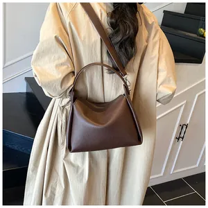 Détail du sac seau marron foncé avec motif litchi, poignée et large bandoulière