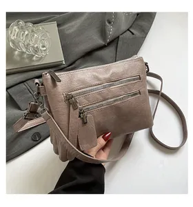 Gros plan sur le sac bandoulière mauve mat doté de multiples poches zippées en métal