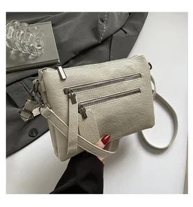 Détail d'un sac bandoulière crème en cuir PU grainé avec deux fermetures à glissière