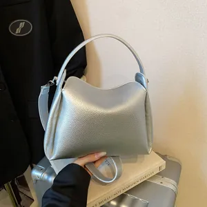 Sac seau argenté avec texture litchi et poignée supérieure sur une valise