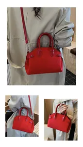 Détail d'un sac à bandoulière rouge mat avec rivets argentés et doubles anses chic