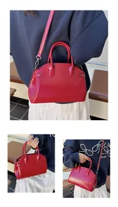 Détail du sac coquille rouge brillant montrant la texture cuir et les deux anses